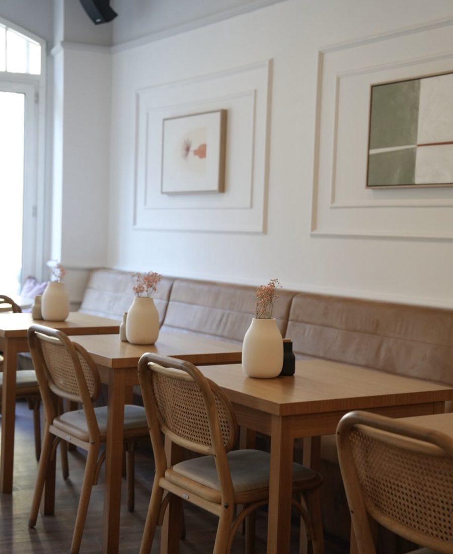 Sitzbank mit Holztischen, Vasen und Bildern im marmell café Freiburg