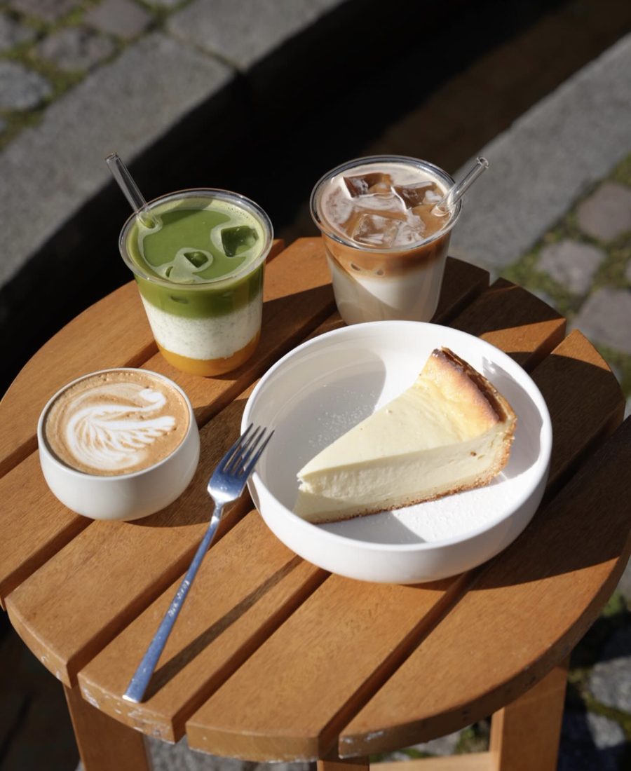 Cappuccino, Iced Matcha, Iced Latte und ein Stück Cheesecake auf der Terrasse des marmell café